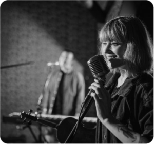 A woman holding a microphone and singing into a microphone.